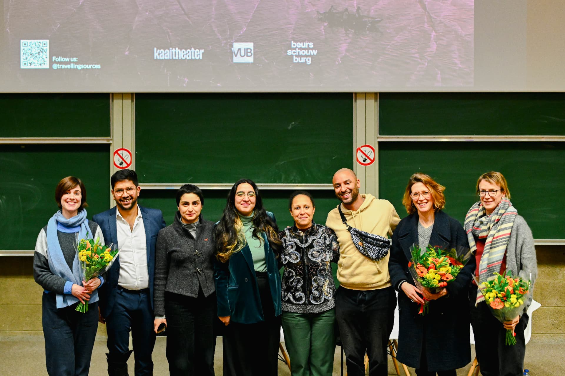 Group of organisers holding flowers in front of a chalkboard